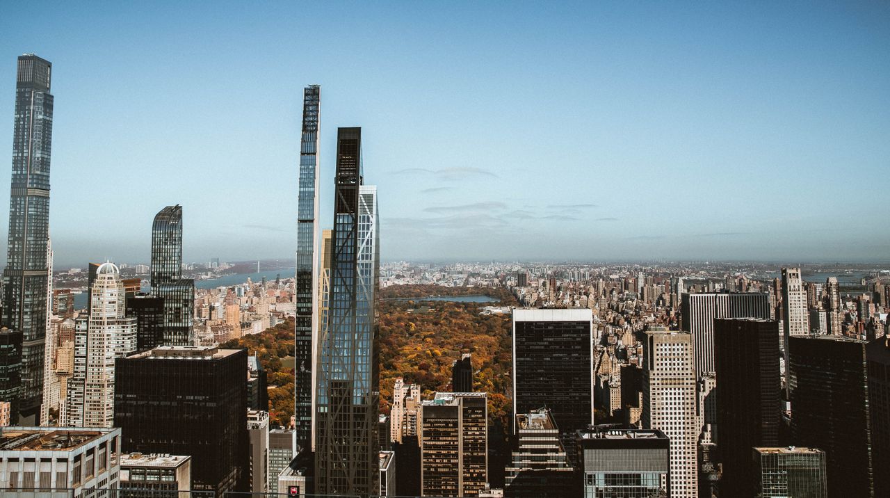 High-rise view overlooking Central Park and New York skyscrapers under a clear blue sky.